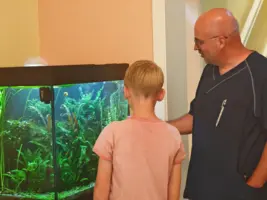Ein Pfleger zeigt einem Kind das Aquarium im Eingang des Hospizes.